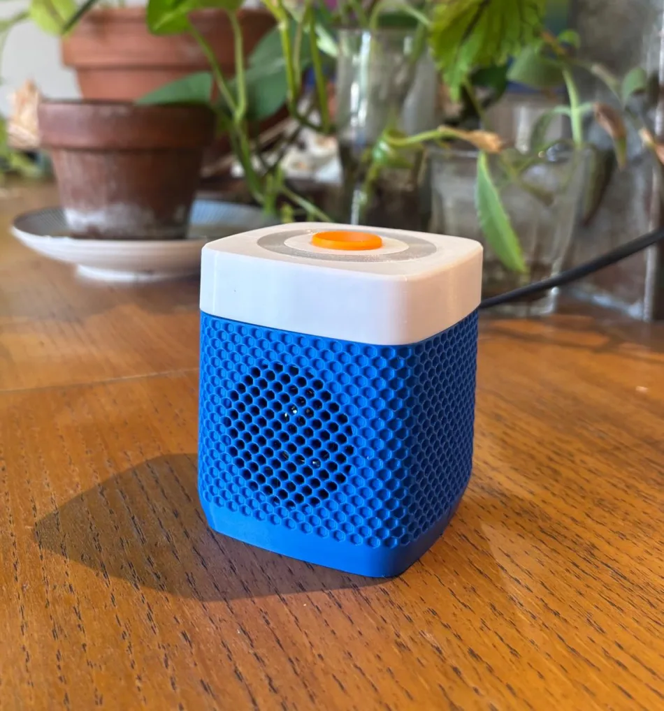Amidou posé sur une table du salon : corps bleu royal, couvercle blanc, bouton tangerine